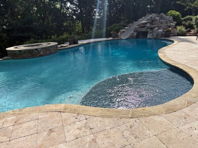 Lagoon pool with rock waterfall, Raised spa, travertine deck
