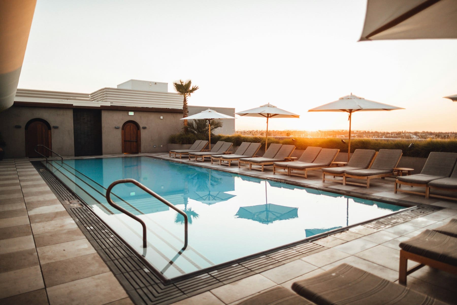 Backyard pool at sunset with a travertine deck and desert mountains behind it